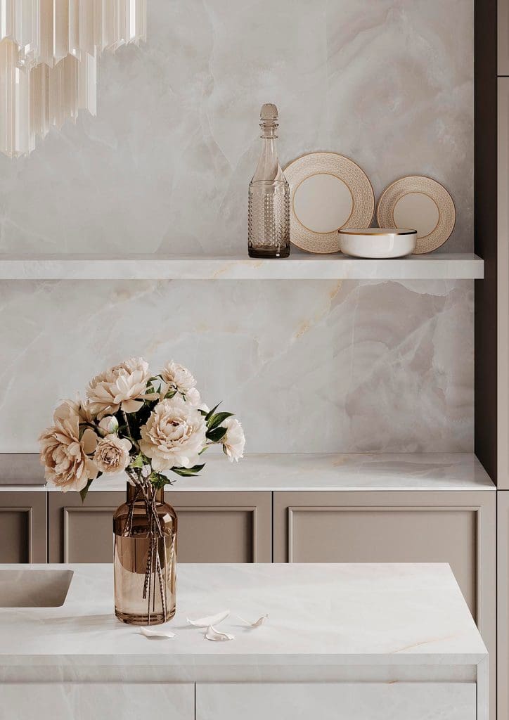 Elegant kitchen with Infinity porcelain, Onyx White countertop and backsplash, taupe cabinetry, and a vase of cream flowers.