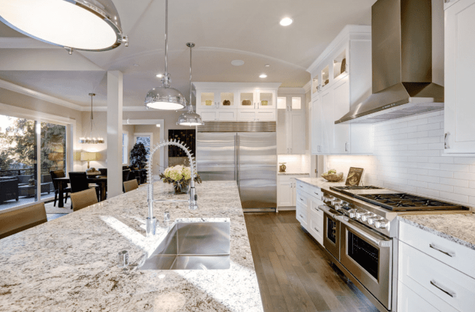 Bright kitchen with speckled granite countertops, stainless steel appliances, and white cabinetry.