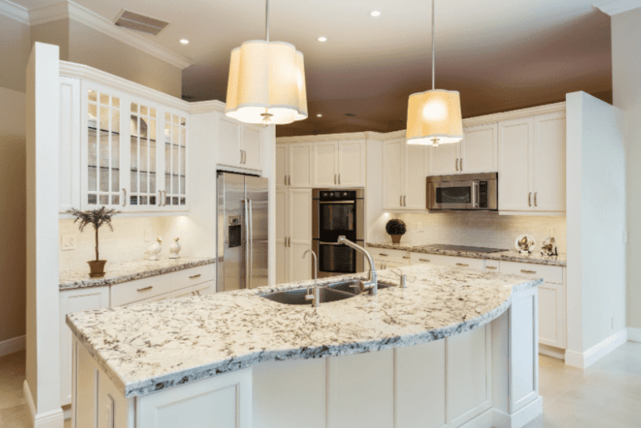 Elegant kitchen with curved granite island, pendant lighting, and white cabinetry.