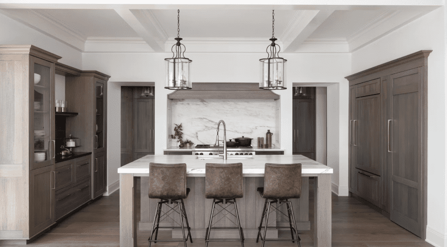 Modern kitchen with Danby marble countertops, wood flooring, and black and brown barstools chairs around a dining island.