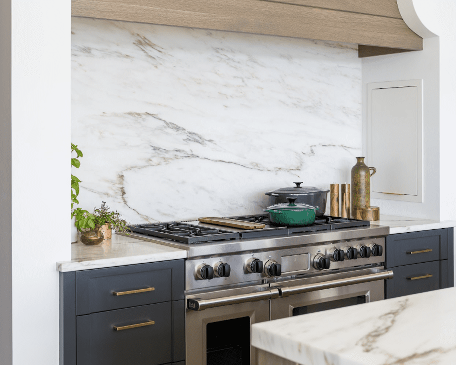 White, gray, and gold marble countertop and backsplash in a rustic kitchen. 