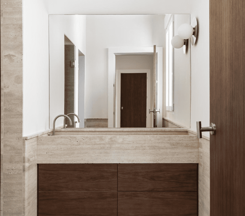 Travertine bathroom vanity with integrated sink and large mirror.