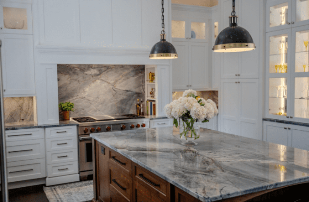 A kitchen countertop in Ijen Quartzite with white cabinets and modern light fixtures. 