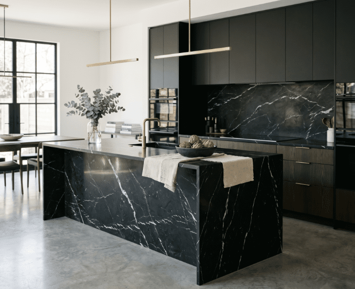 Dark kitchen with Nero Marquina stone island and backsplash featuring bold white veining.
