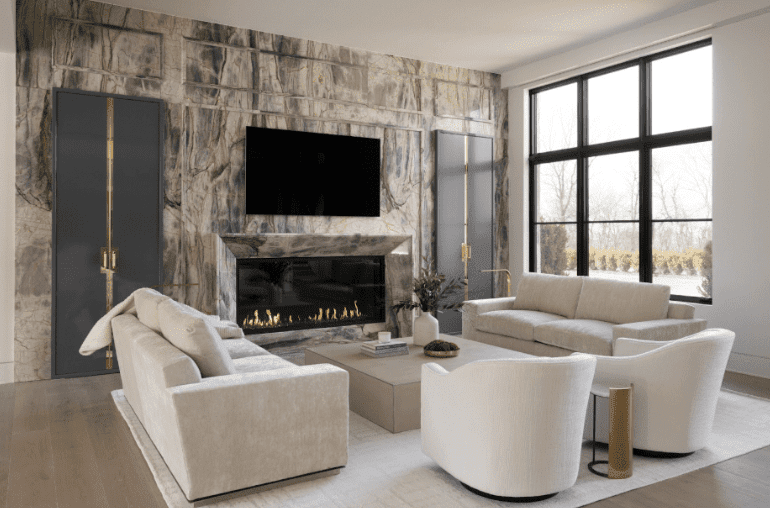 Modern living room with stone fireplace wall, mounted TV, and neutral seating.