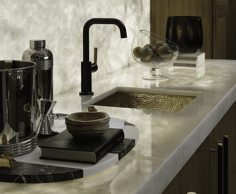 Close-up of a Cristallo quartzite countertop with a hammered brass sink and matte black faucet.