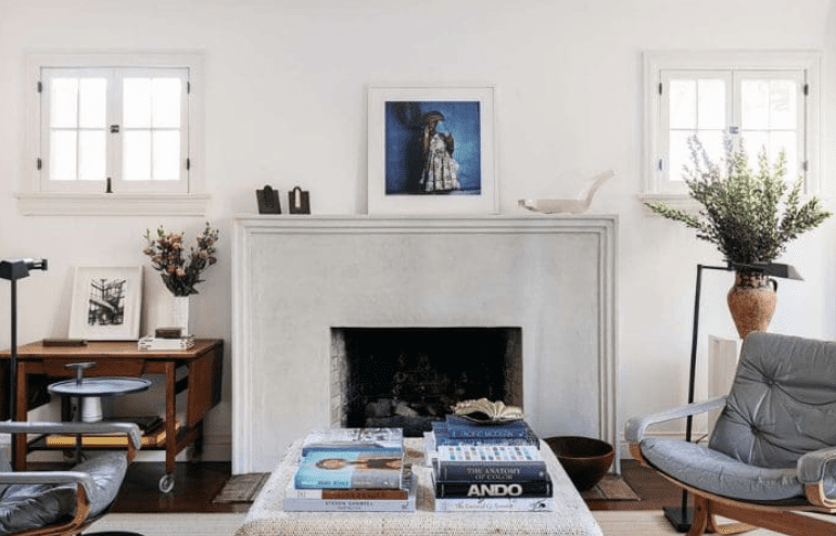 White limestone fireplace surround with simple mantel in a bright living room.