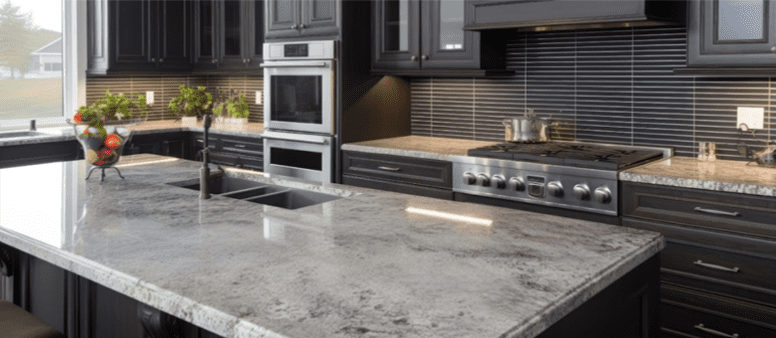 A modern kitchen with dark cabinets and light toned granite countertops.