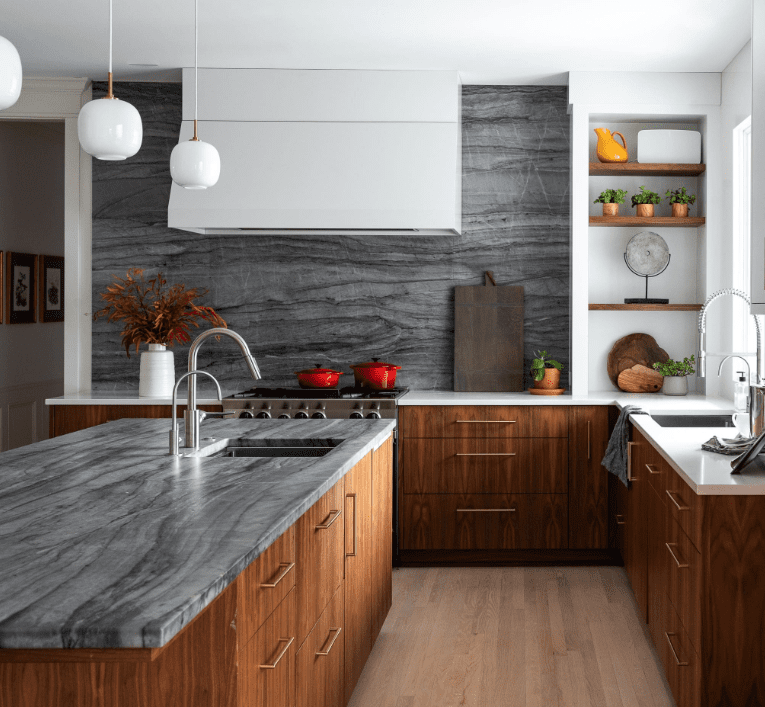 Gray quartzite island countertop and backsplash paired with walnut cabinets and white perimeter countertops.