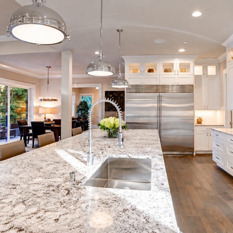 White kitchen with granite island countertop, stainless steel appliances, and a subway tile backsplash.